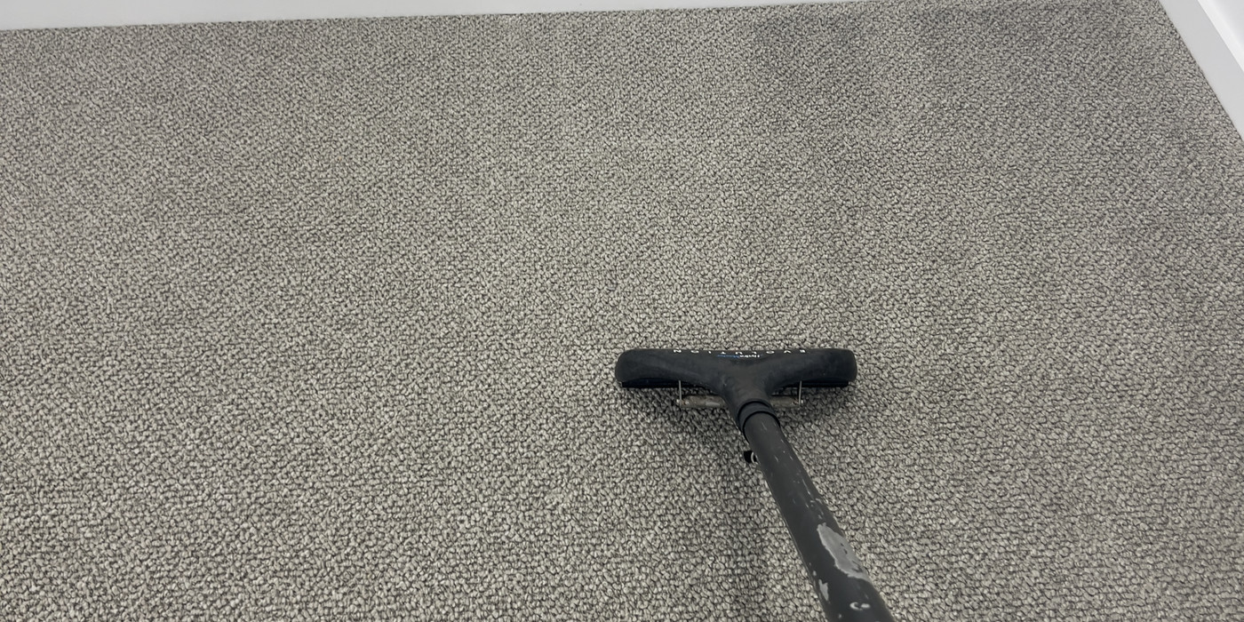 Cleaning wand mid-stroke on bedroom carpet during an end of lease job