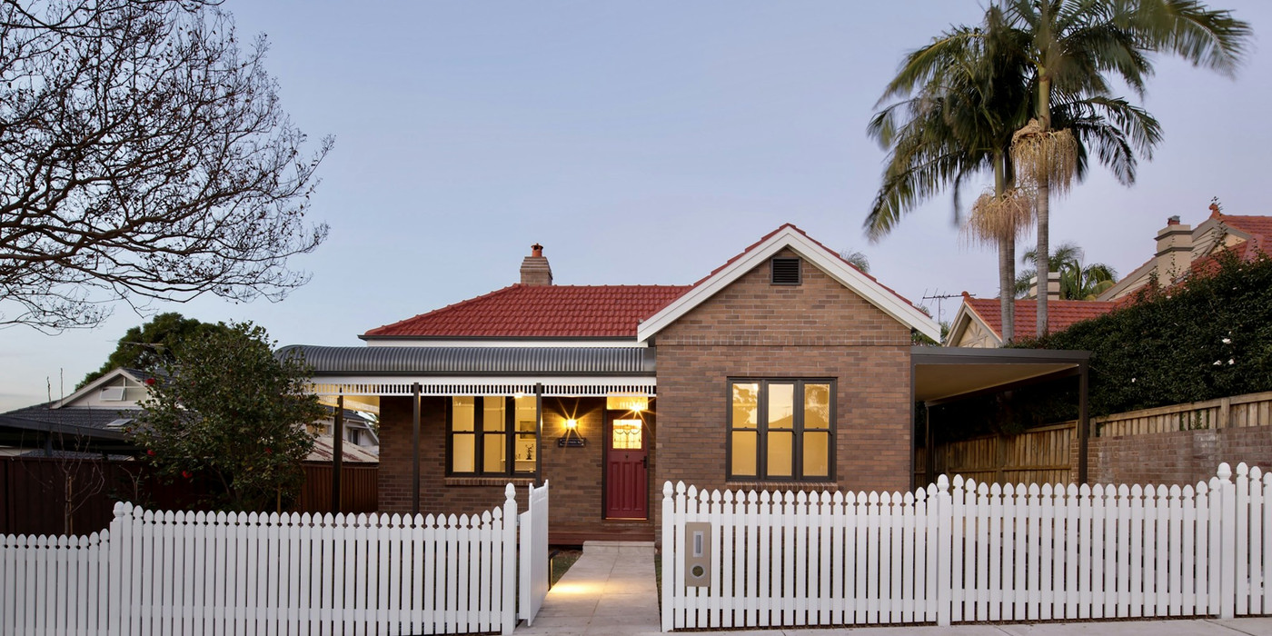 A brick house with a picket fence out the front