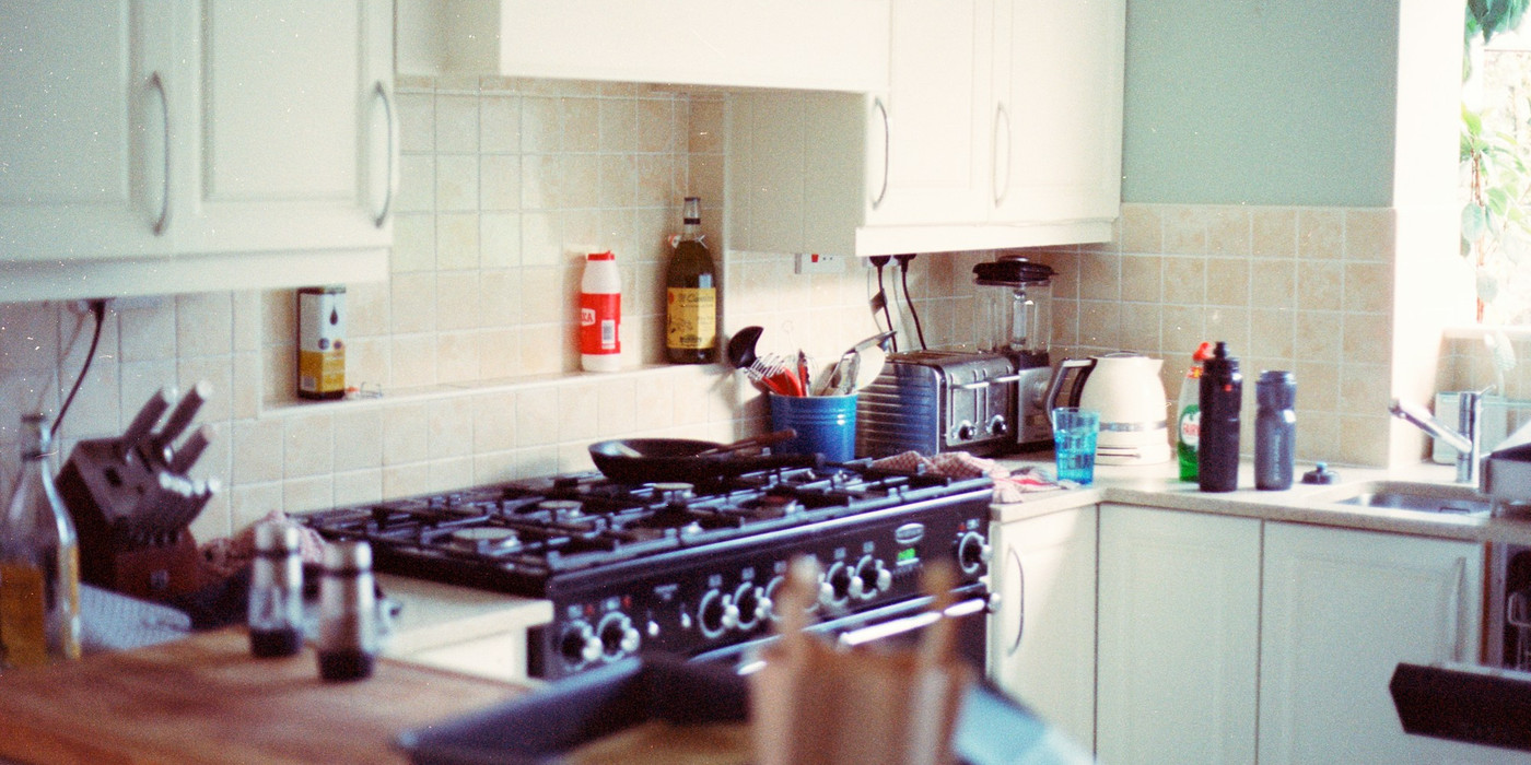 A lived-in kitchen with a black freestanding gas oven and cooktop against a tiled splashback